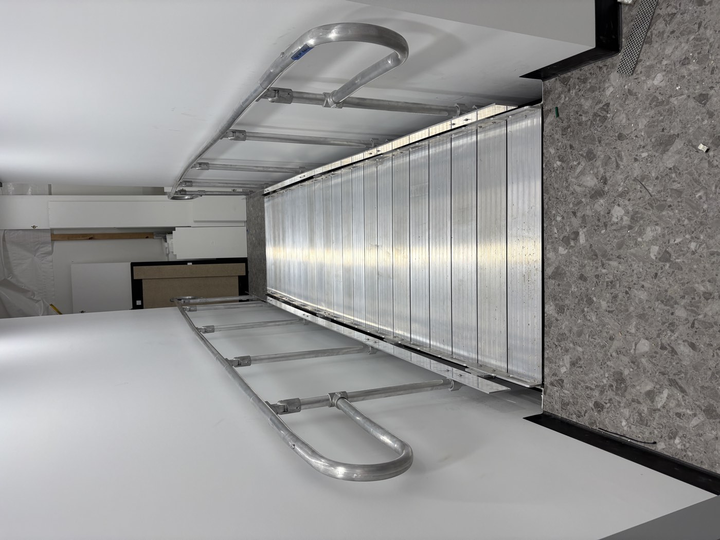 Modular aluminium access ramp with handrails to both sides, viewed from the top landing, on a retail fitout in Rye.